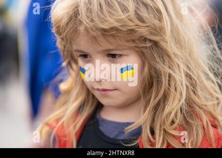 Ukraine flag on kids cheek. World stand With Ukraine. Stock Photo