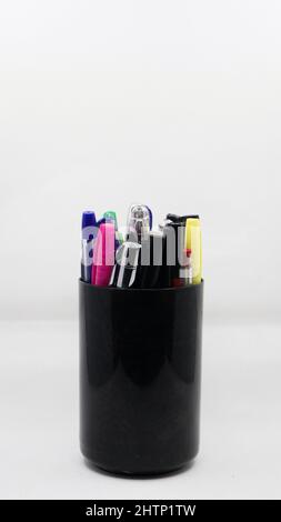 different varieties of gel, ball and colorful pens in a black pen holder isolated in a white background Stock Photo