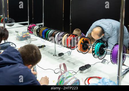 Visitors to the exhibition of modern technologies test 3D pens on a special stand equipped with pens and plastic of various colors. Stock Photo