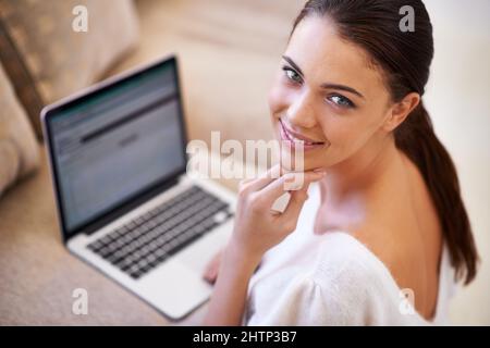 Connecting with friends has never been easier. Shot of a young woman sitting in her living room using a laptop. Stock Photo