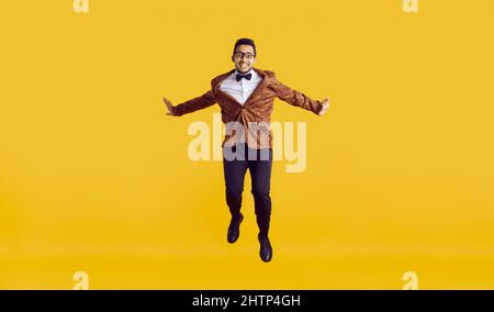 Studio shot of a happy funny young black man in a leopard jacket jumping high in the air Stock Photo
