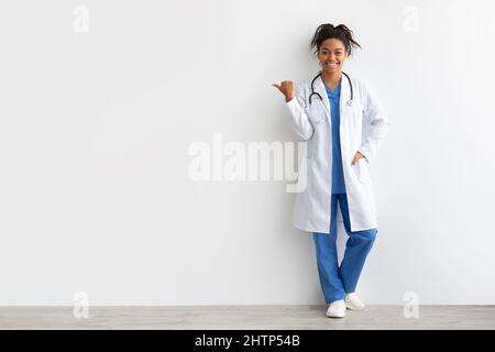 Cheerful female black doctor smiling pointing at copy space Stock Photo