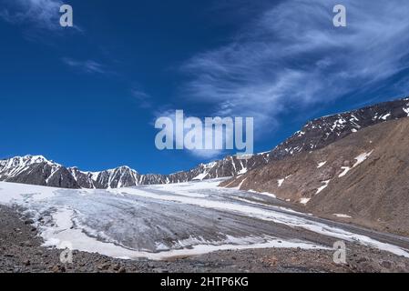 Amazing summer view with beautiful fluffy cirrus clouds in the blue sky over the glacier, snowy peaks and mountains. Altai, Russia Stock Photo