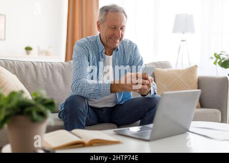 Portrait of smiling mature man using smartphone at home Stock Photo