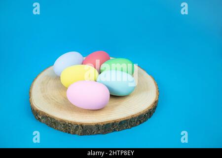 Easter, plain, multi-colored eggs on a hemp plate on a blue background Stock Photo