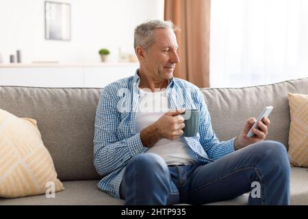 Portrait of smiling mature man using smartphone at home Stock Photo