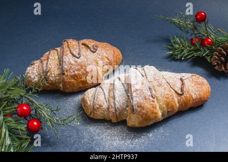 Selective focus shot of croissants with holiday ornaments on a black surface Stock Photo