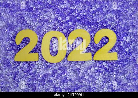 2022 is written in wooden numbers on purple beads. Stock Photo