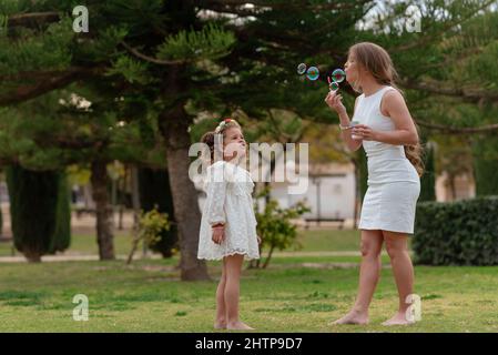 Mother and daughter blow soap bubbles outdoors. Stock Photo