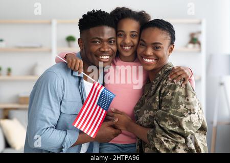 Happy girl with flag of US hugging her parents Stock Photo