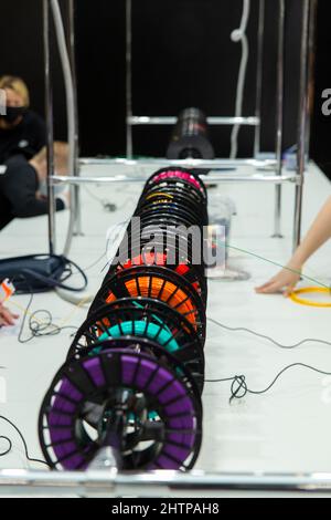 Colorful rainbow plastic filaments on bobbins and some 3D pens laying on white background. Visitors to the exhibition of modern technologies test 3D p Stock Photo