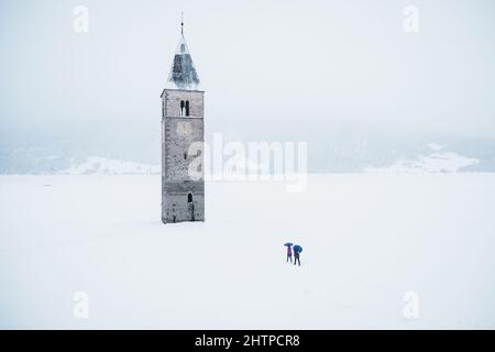 Beautiful shot of the tower in the middle of the Lake Reschen during winter in South Tyrol, Italy Stock Photo