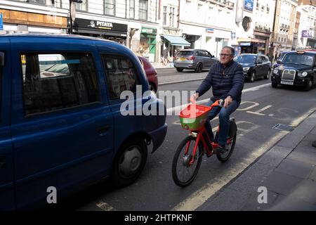 Man riding a Lime bike, once called Jump, dockless bike sharing electric cycle on 17th February 2022 in London, United Kingdom. Neutron Holdings Inc. doing business under the name Lime, formerly LimeBike, is a transportation company based in USA. It runs electric scooters, electric bikes, normal pedal bikes, electric mopeds and car sharing systems in various cities around the world. Stock Photo