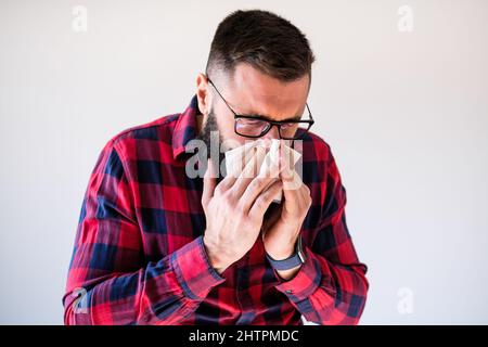 Portrait of man who blowing his nose because of allergy. Copy space on image for your text or advert.