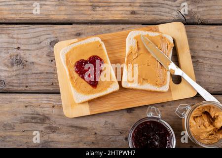 Close-up of open face peanut butter and jelly sandwich on serving board with jars at table Stock Photo