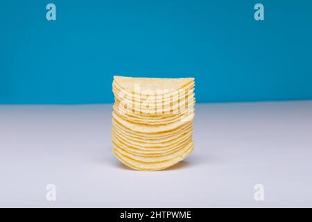 Close-up of stacked potato chips on table against blue background with copy space Stock Photo