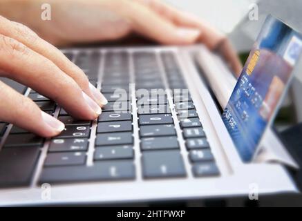 Closeup of a credit card on a laptop keyboard with a person typing. Online shop concept Stock Photo