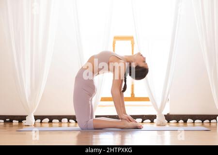 Young woman doing ustrasana or camel pose. Stock Photo