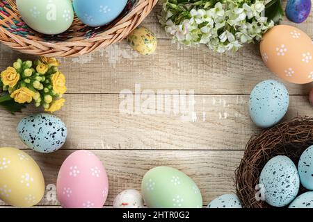 Border of easter eggs and flowers around a rustic wooden background Stock Photo