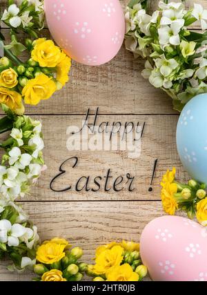 Easter border of decorated eggs and flowers on a rustic wooden background with Happy Easter text Stock Photo
