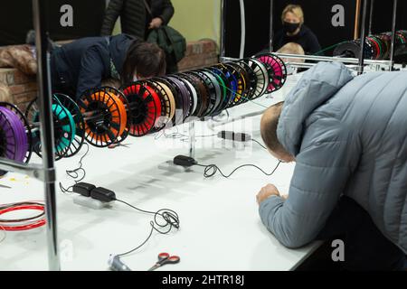 Visitors to the exhibition of modern technologies test 3D pens on a special stand equipped with pens and plastic of various colors. Stock Photo