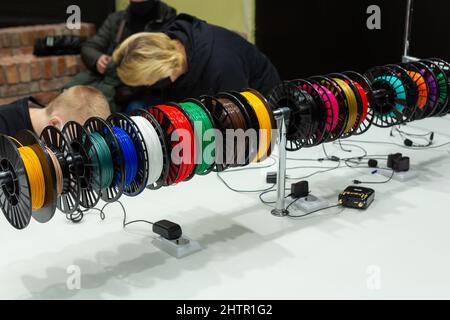 Visitors to the exhibition of modern technologies test 3D pens on a special stand equipped with pens and plastic of various colors. Stock Photo