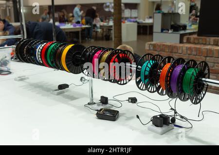 Visitors to the exhibition of modern technologies test 3D pens on a special stand equipped with pens and plastic of various colors. Stock Photo