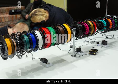 Visitors to the exhibition of modern technologies test 3D pens on a special stand equipped with pens and plastic of various colors. Stock Photo