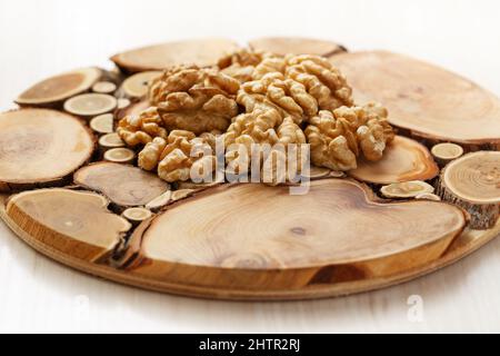Peeled halves of walnuts on a tray made from slices of tree trunks. Close up Stock Photo