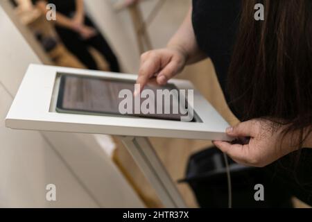 A woman checking in at a medical wellness spa using an electronic tablet to gather her personal data and sign medical waivers and forms Stock Photo