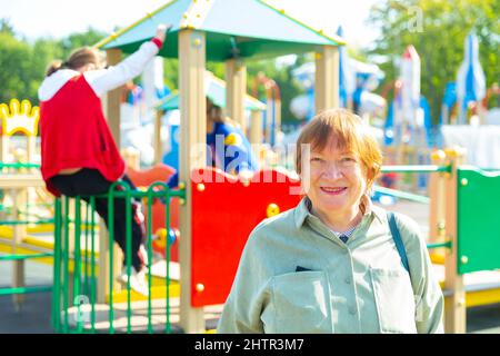 Grandmother walks with her grandchildren on playground Stock Photo