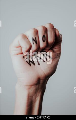 the raised fist of a man, with the text no war written in it, on a pale gray background Stock Photo
