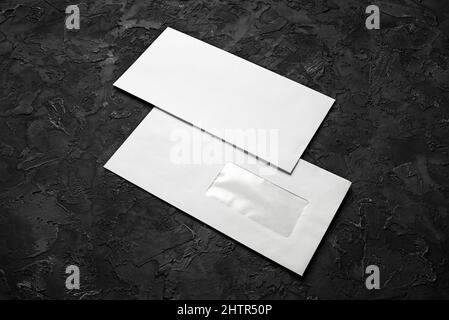 Two blank paper envelopes on black stone background. Back and front. Stock Photo