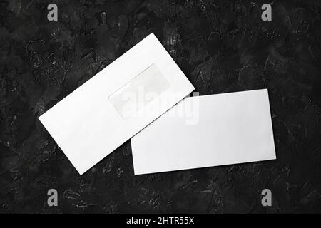 Blank white paper envelopes on black stone background. Front and back side. Template for your design. Flat lay. Stock Photo