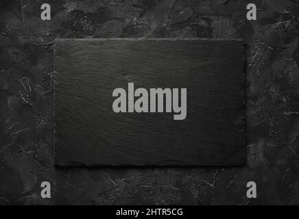 Black stone slate plate on black stone background. Copy space for text. Flat lay. Stock Photo