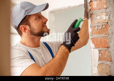 Portrait of smiling handyman or craftsman filling the wall, preparing it for painting Stock Photo
