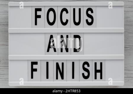 'Focus and Finish' on a lightbox on a white wooden background, top view. Flat lay, overhead, from above. Stock Photo