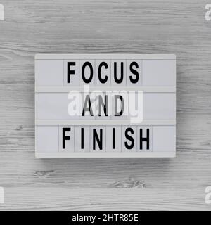 'Focus and Finish' on a lightbox on a white wooden surface, top view. Flat lay, overhead, from above. Stock Photo