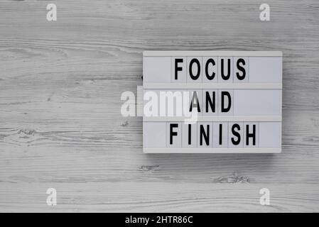 'Focus and Finish' on a lightbox on a white wooden background, top view. Flat lay, overhead, from above. Stock Photo