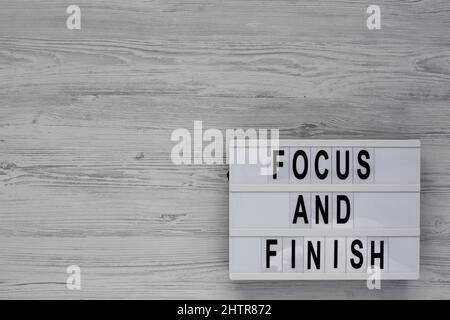 'Focus and Finish' on a lightbox on a white wooden surface, top view. Flat lay, overhead, from above. Stock Photo