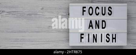 'Focus and Finish' on a lightbox on a white wooden background, top view. Flat lay, overhead, from above. Stock Photo