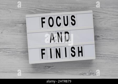 'Focus and Finish' on a lightbox on a white wooden surface, top view. Flat lay, overhead, from above. Stock Photo