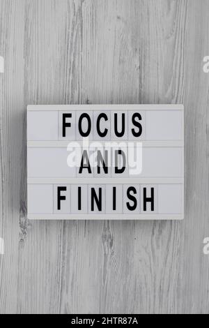 'Focus and Finish' on a lightbox on a white wooden surface, top view. Flat lay, overhead, from above. Stock Photo