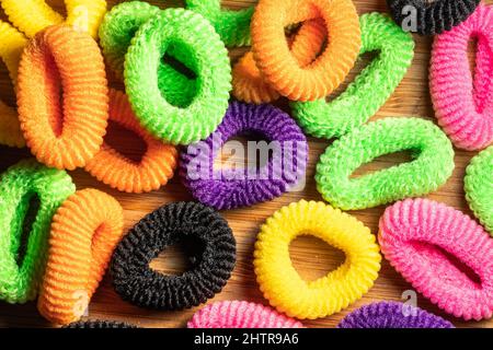 Lots of multi-colored hair elastic bands tied together with crunchies. Hair care and fashion. Multicolored hair accessories, isolated objects on woode Stock Photo