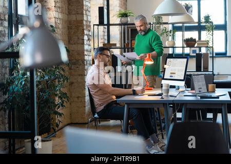 Two businessmen cooperating each other at modern office using laptop and documents, they preparing for the presentation Stock Photo