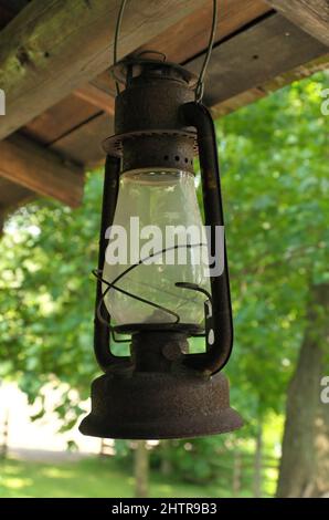 Rusty Kerosene oil lamp hanging from a rustic wooden porch Stock Photo