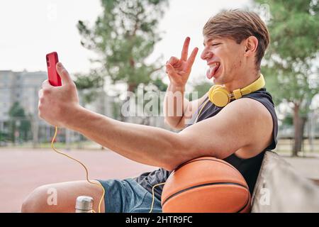 basketball player resting. male athlete sitting while making a video call on his mobile phone. Stock Photo