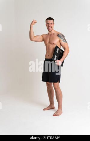 Man with weights health pondered, health and sports on a white background back hurt injury, cramp spine isolated young adult, illness expression Stock Photo