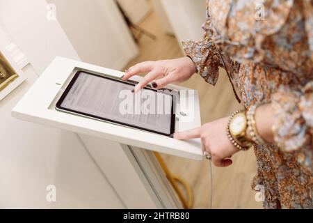 A woman checking in at a medical wellness spa using an electronic tablet to gather her personal data and sign medical waivers and forms Stock Photo