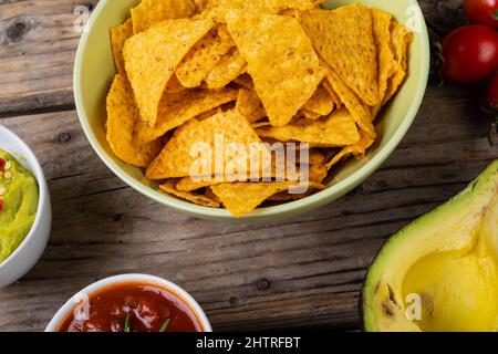 Close-up of nacho chips in bowl with dips and vegetables on table Stock Photo